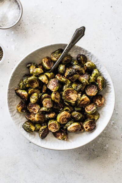 Honey Balsamic Brussel Sprouts in a white bowl topped with sea salt.