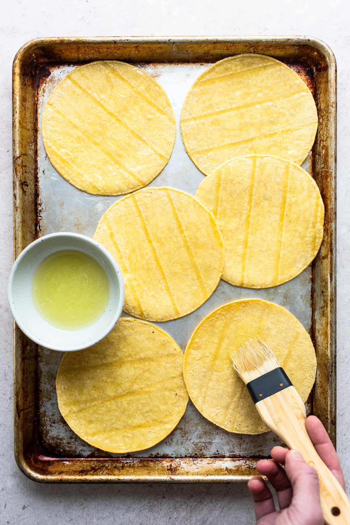 Oil being brushed onto corn tortillas.