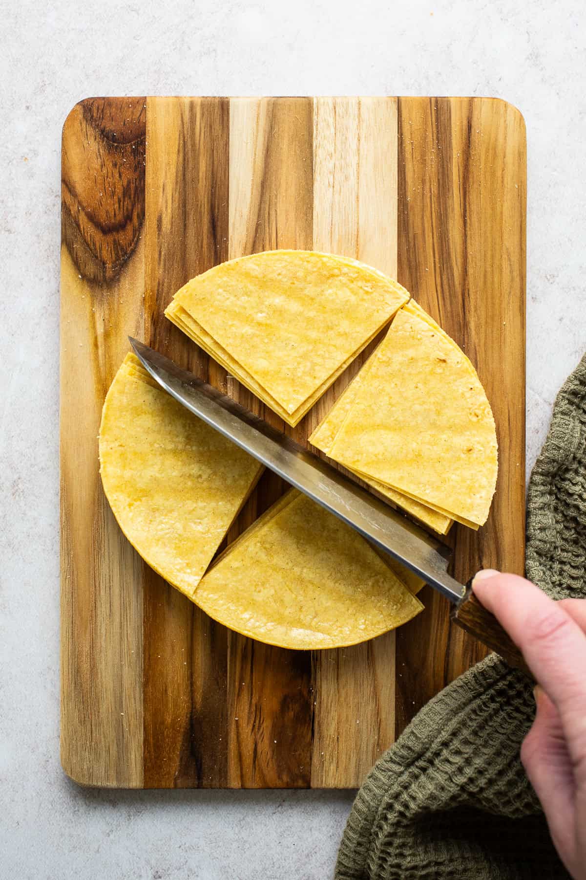 Corn tortillas being cut into triangle wedges for baked tortilla chips.