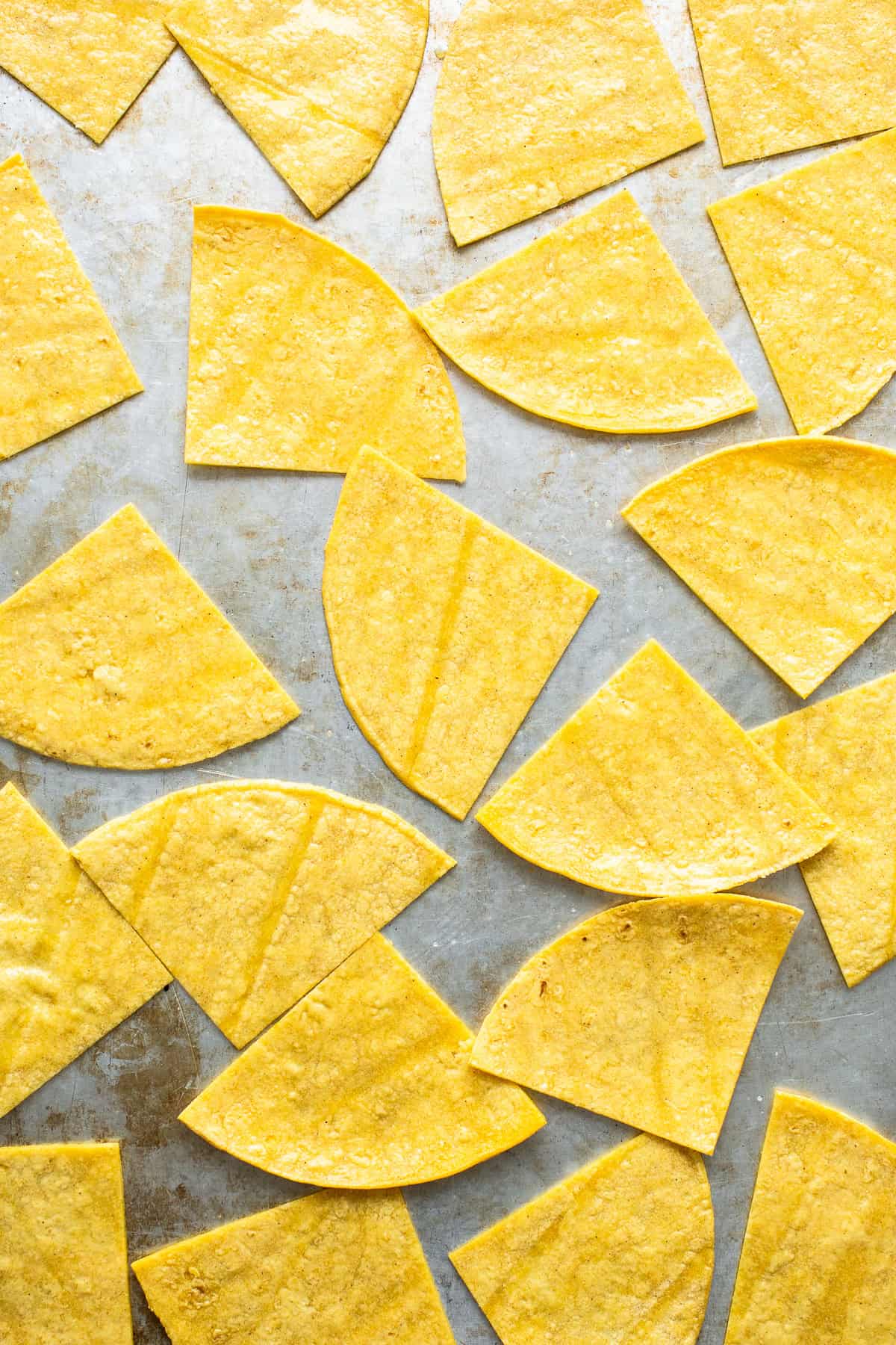 Cut corn tortilla triangles on a baking sheet before baking.