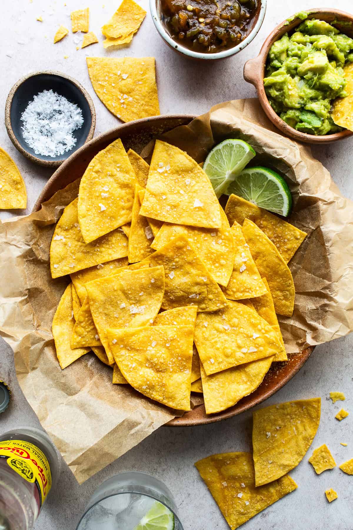 Crispy baked tortilla chips in a bowl garnished with flaky sea salt and lime wedges for a squeeze of citrus.