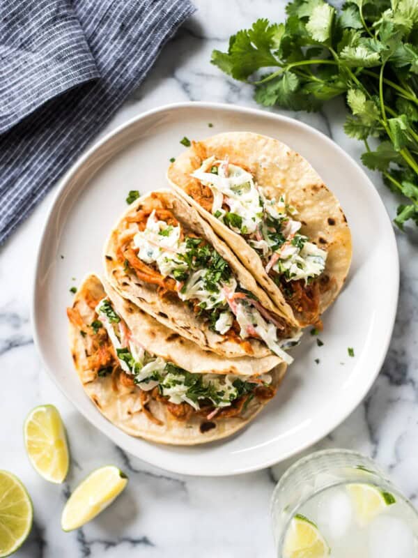 These Slow Cooker BBQ Pulled Pork Tacos served with a cilantro lime coleslaw are easy to make and perfect for healthy weeknight meals! The recipe is gluten free and freezer-friendly.