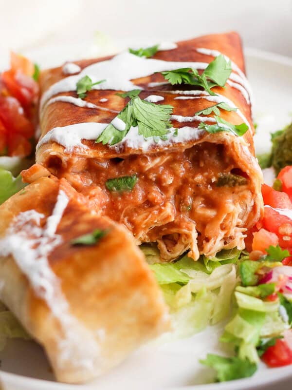 A chimichanga filled with shredded chicken, refried beans, salsa, and cheese sliced in half to see the inside.