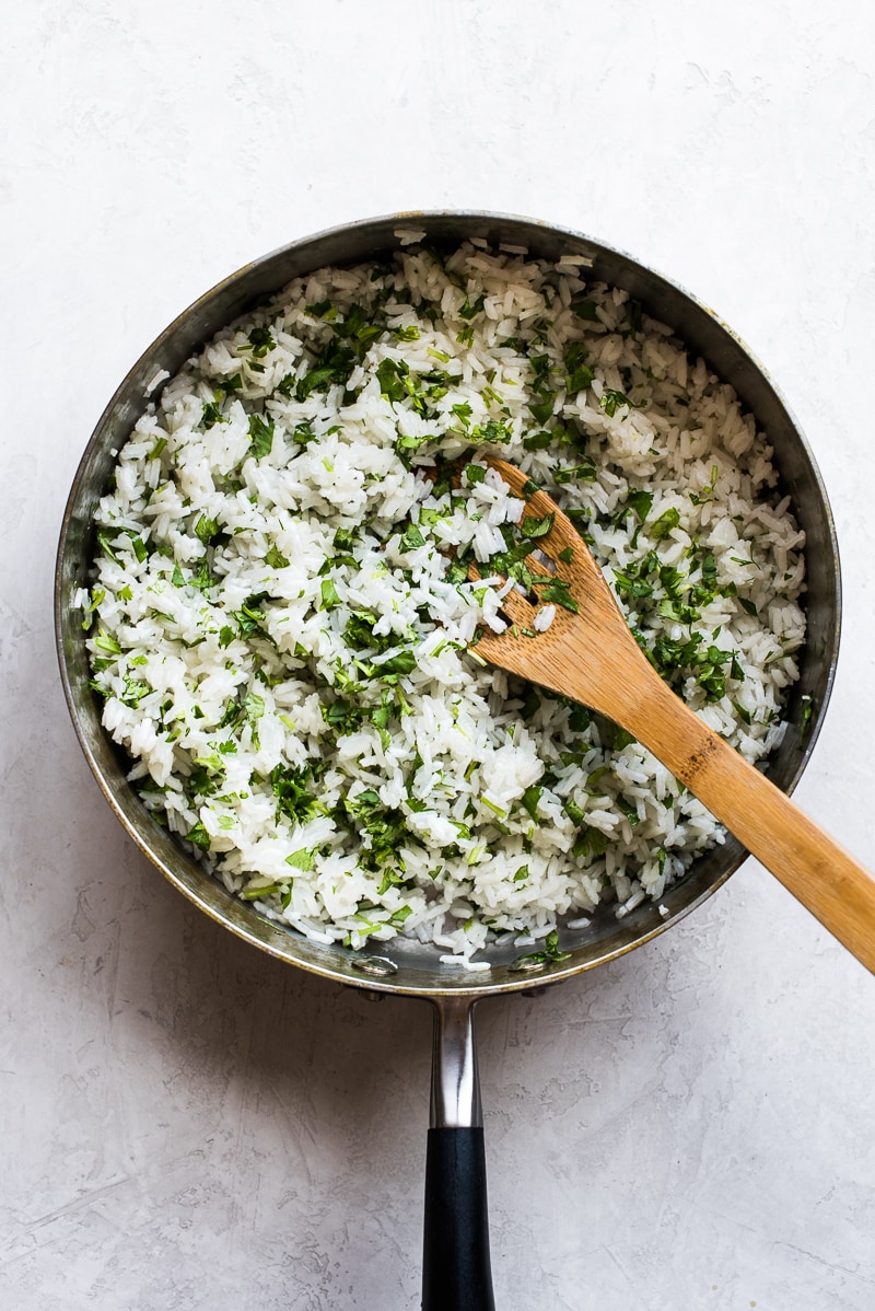 Arroz con lima y cilantro en una olla con cuchara de madera