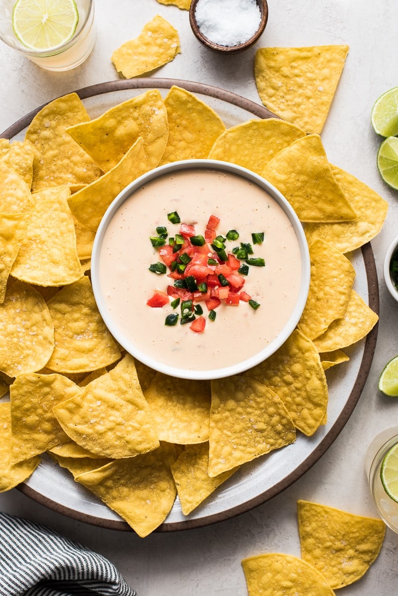Bowl of queso dip surrounded by tortilla chips.