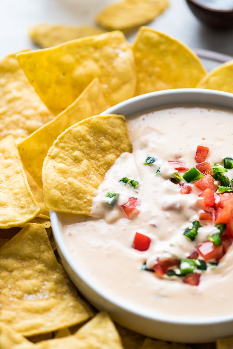 Mexican queso dip with a tortilla chip dipped in it.