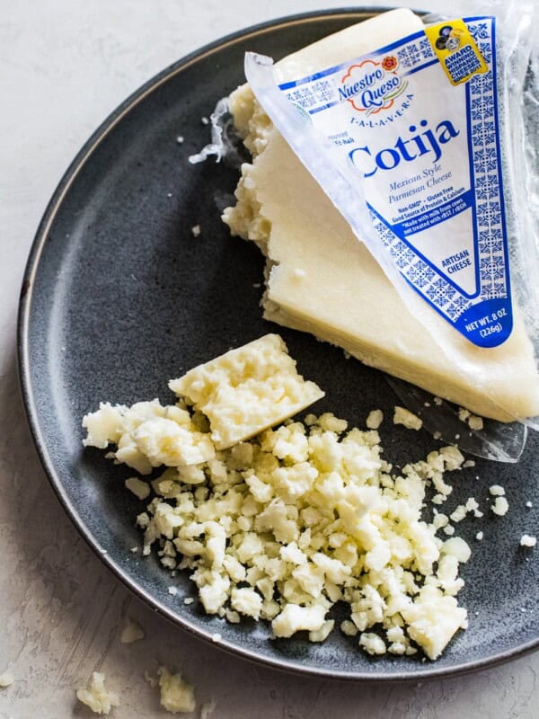 Crumbled cotija cheese on a gray stone plate.