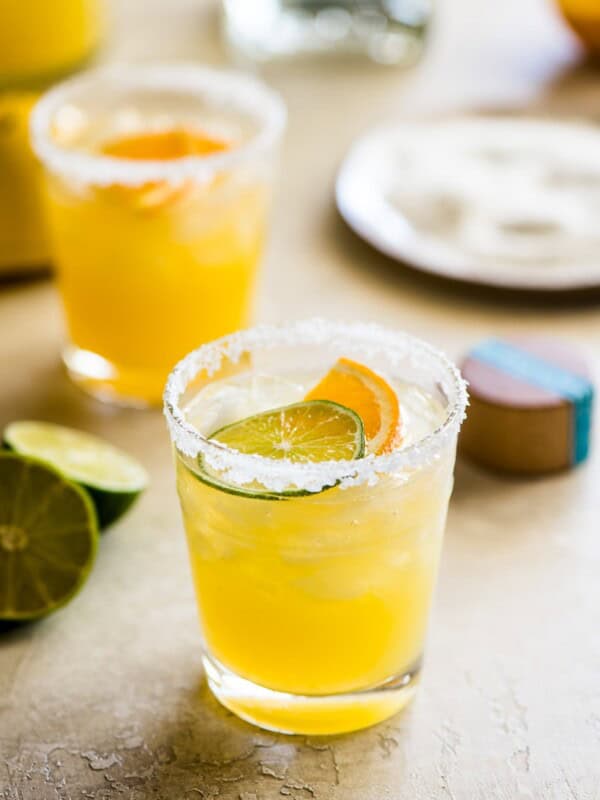 Skinny margarita cocktail glass garnished with sliced lime and orange.