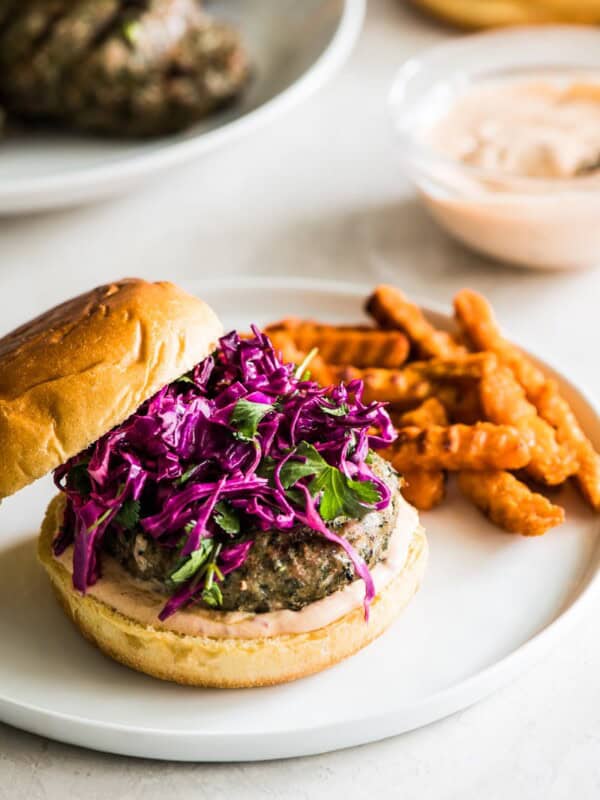 A grilled turkey burger sitting on a hamburger bun topped with chipotle lime mayo and a red cabbage slaw.