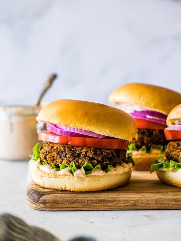 Black Bean Burger on a wooden board with mayo, tomatoes, and lettuce.