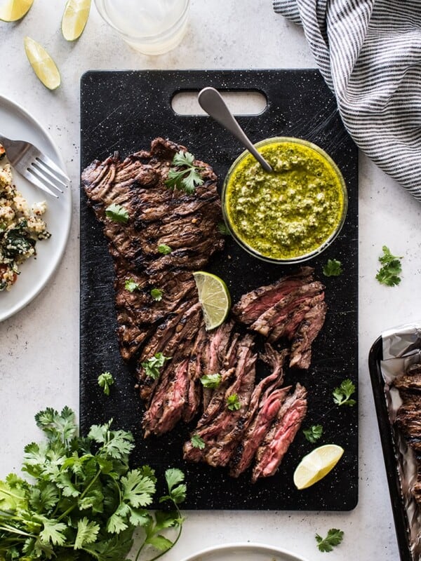 Thinly sliced grilled skirt steak on a cutting board topped with cilantro pesto