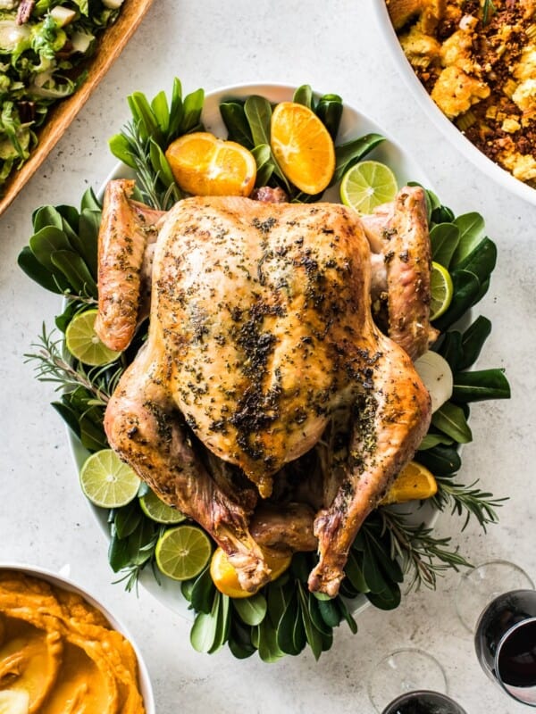 Herb Roast Turkey on a large platter next to Thanksgiving side dishes.