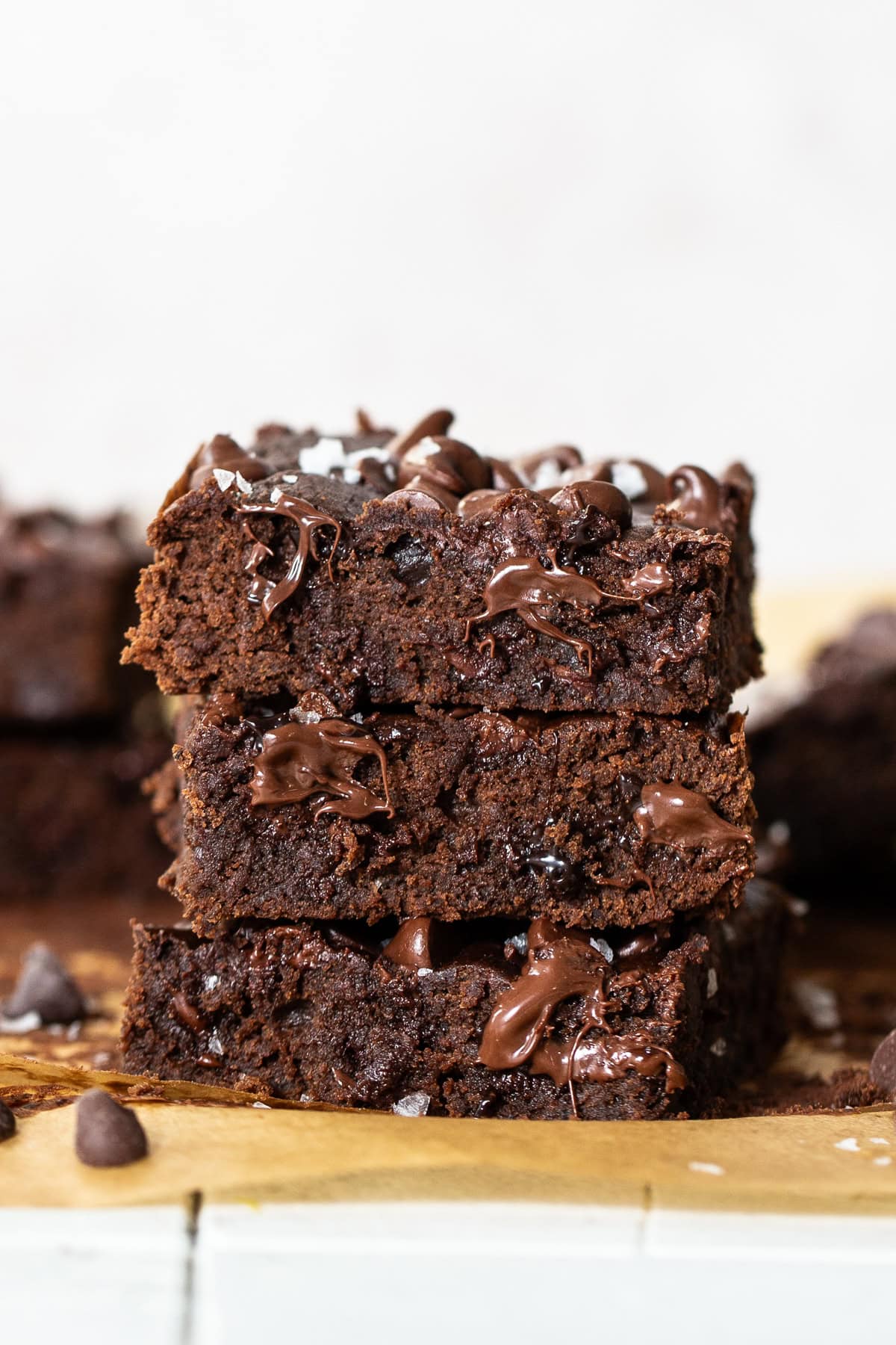 Three black bean brownies stacked on top of one another to revel the gooey chocolate chips inside.