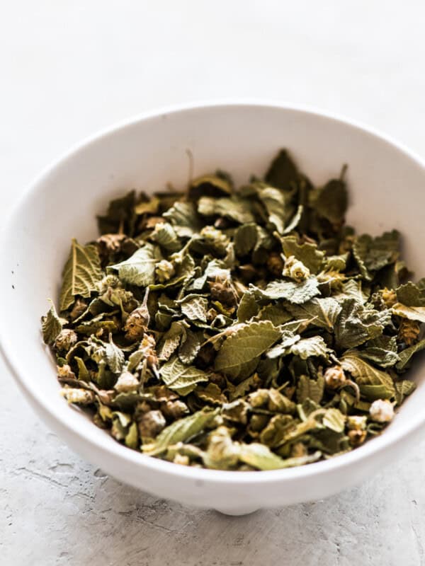 Mexican oregano dried whole leaves in a small white ramekin.