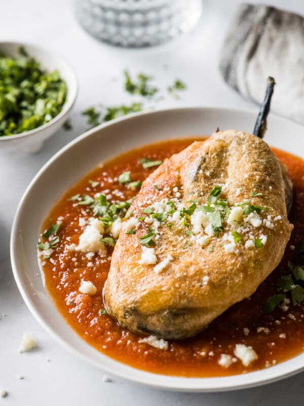 Chile relleno on a plate with red salsa.