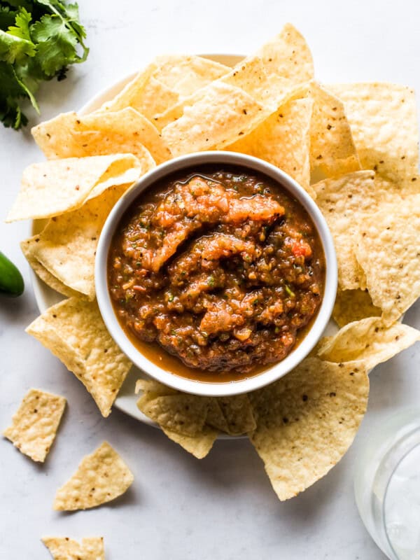 Roasted tomato salsa in a bowl surrounded by tortilla chips.