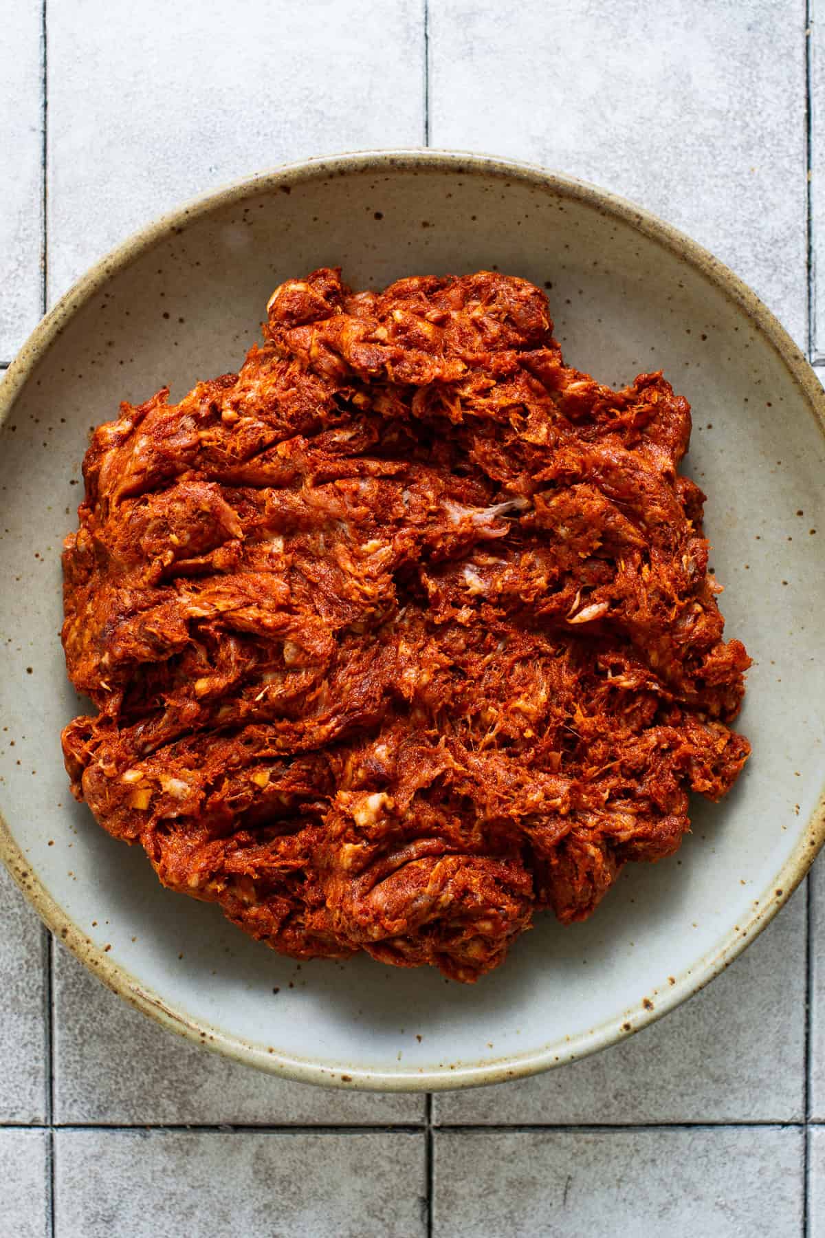 Brightly red-colored and seasoned Mexican chorizo in a bowl before being cooked.