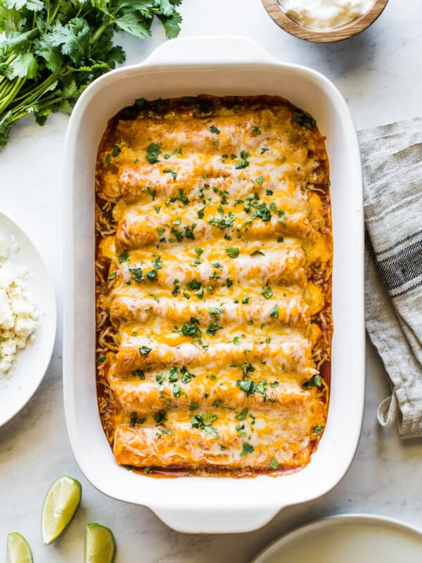 Chicken enchiladas in a baking dish topped with cilantro.