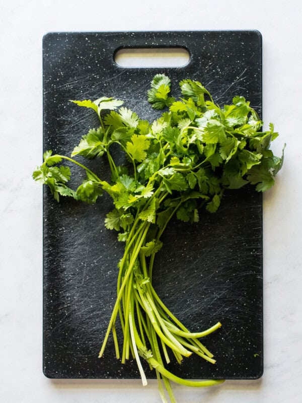 An entire bunch of cilantro on a cutting board.