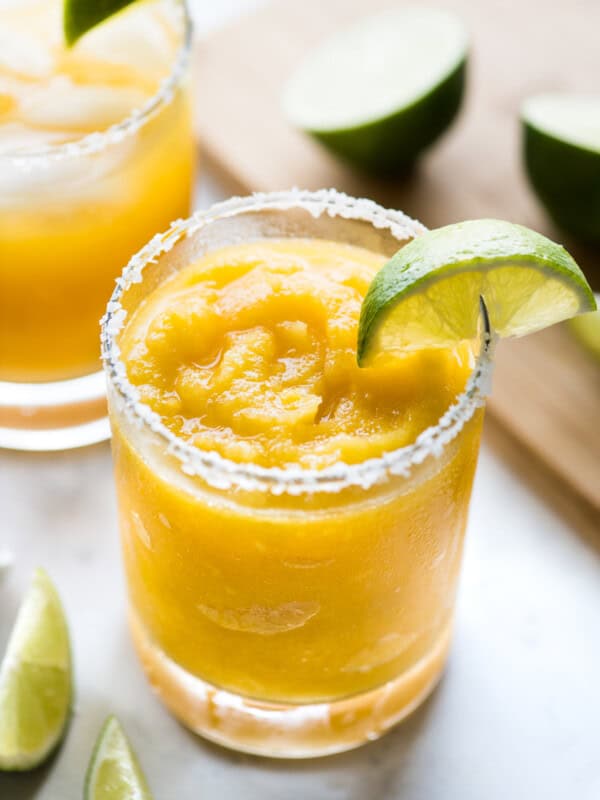 A mango margarita served frozen with a lime wedge.