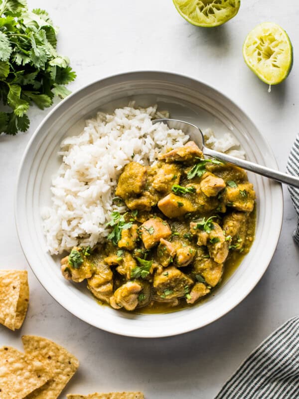 Chicken chile verde in a bowl with white rice topped with cilantro.