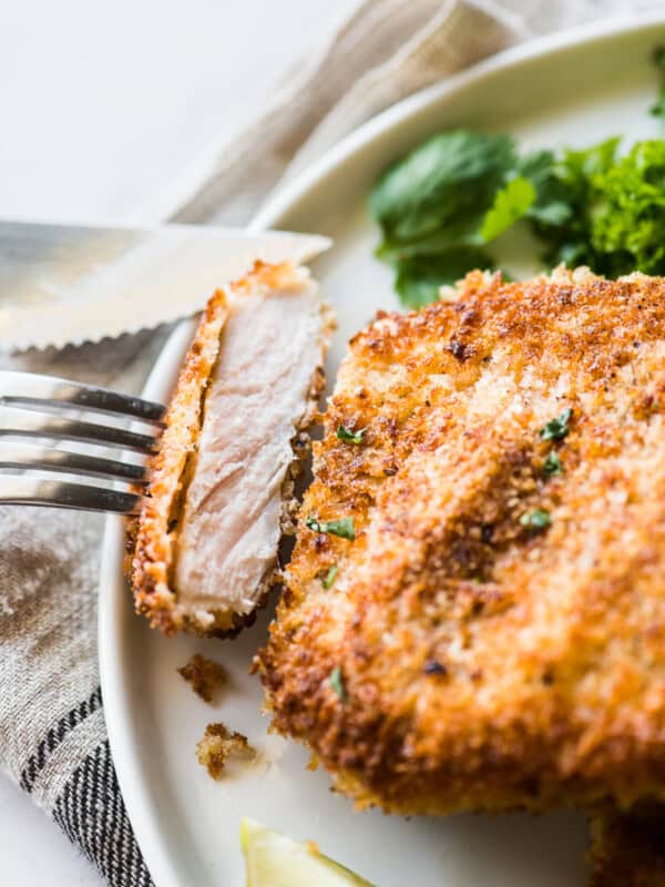 A slice of crispy breaded pork cutlet on a fork ready to eat.