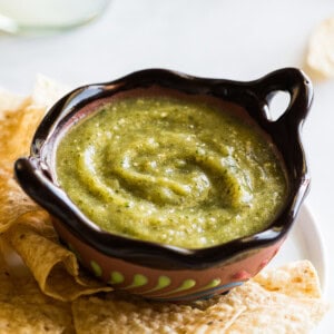 Salsa verde in a Mexican bowl next to some tortilla chips.