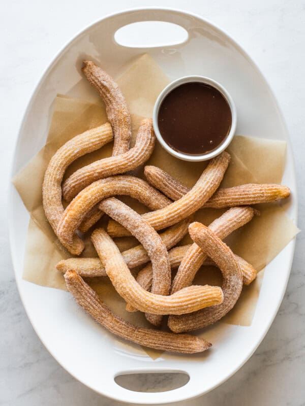 Churros covered in cinnamon sugar with a ramekin of chocolate sauce.