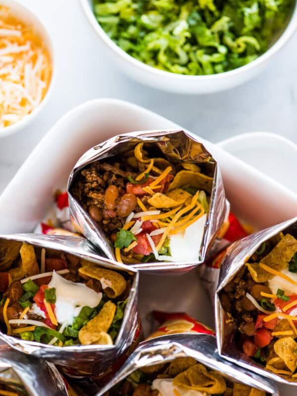 Bags of walking tacos filled with beef, beans, cheese, sour cream, tomatoes, and more.