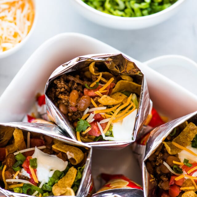 Bags of walking tacos filled with beef, beans, cheese, sour cream, tomatoes, and more.