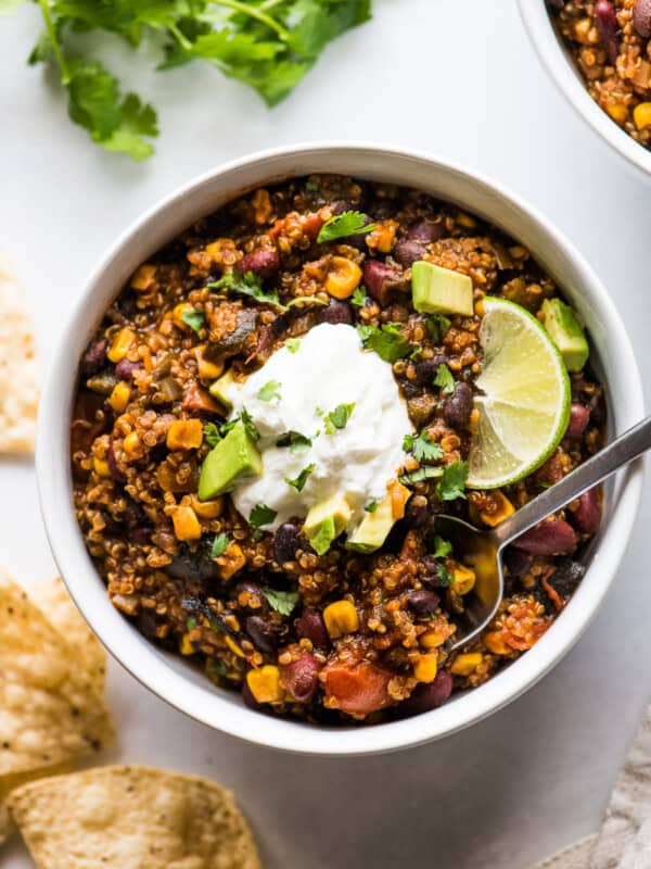 Quinoa black bean chili in a bowl topped with cilantro, avocados, and sour cream.