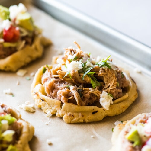 Sopes topped with shredded carnitas and queso fresco.