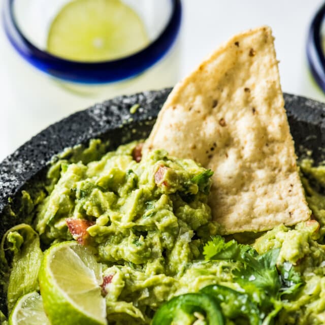 Guacamole in a molcajete with a tortilla chip.