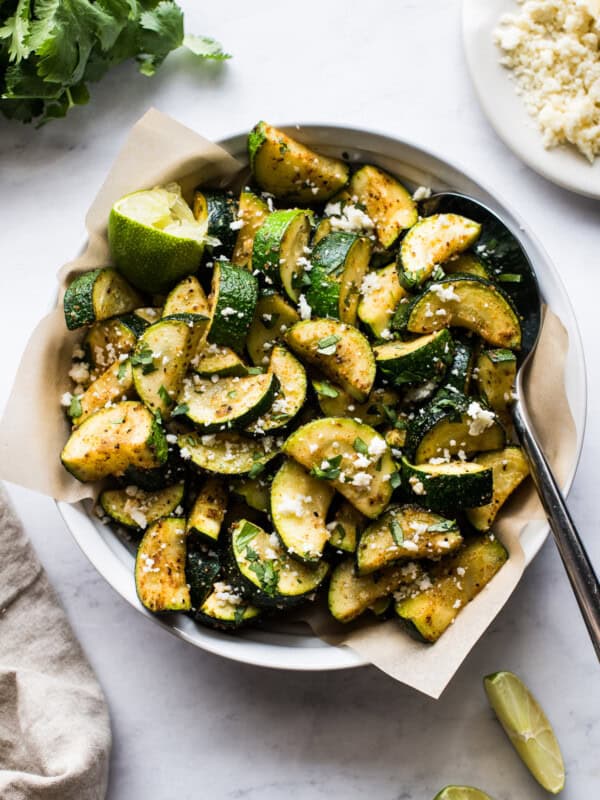 Roasted Mexican Zucchini in a bowl topped with cotija cheese, lime juice, and cilantro.