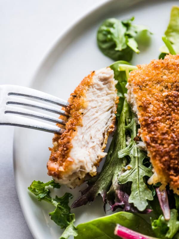 A Milanesa de pollo sliced and ready to eat on a fork.