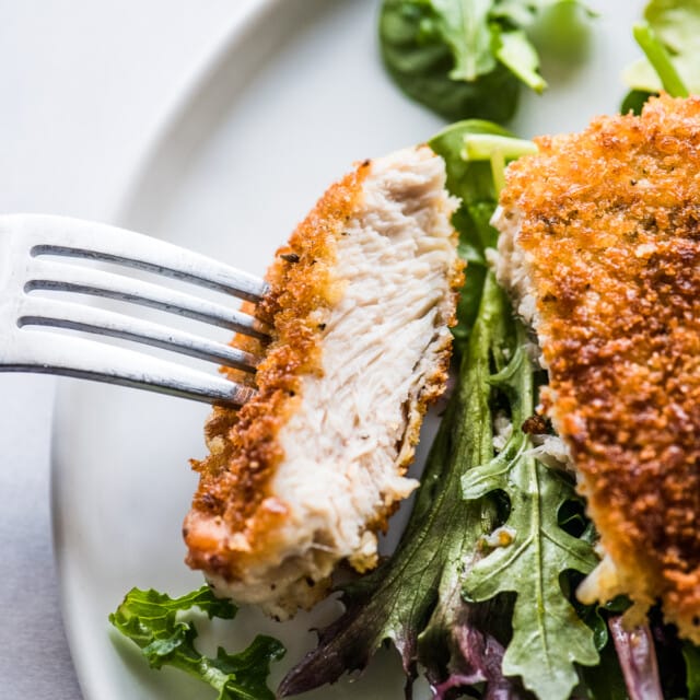 A Milanesa de pollo sliced and ready to eat on a fork.