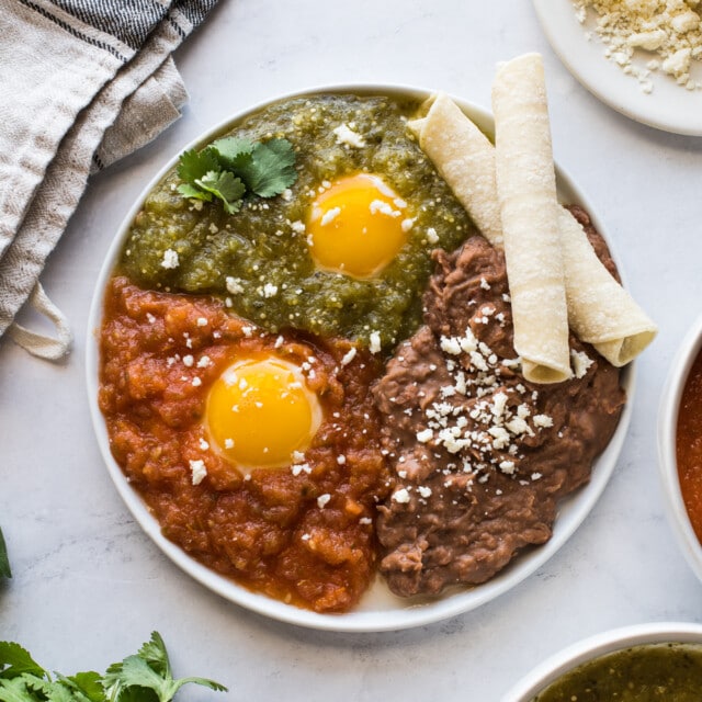 Huevos Divorciados on a plate served with refried beans.