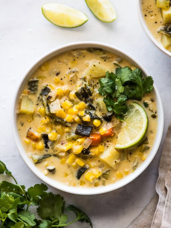 Roasted poblano corn chowder in a bowl topped with cilantro and a lime wedge.