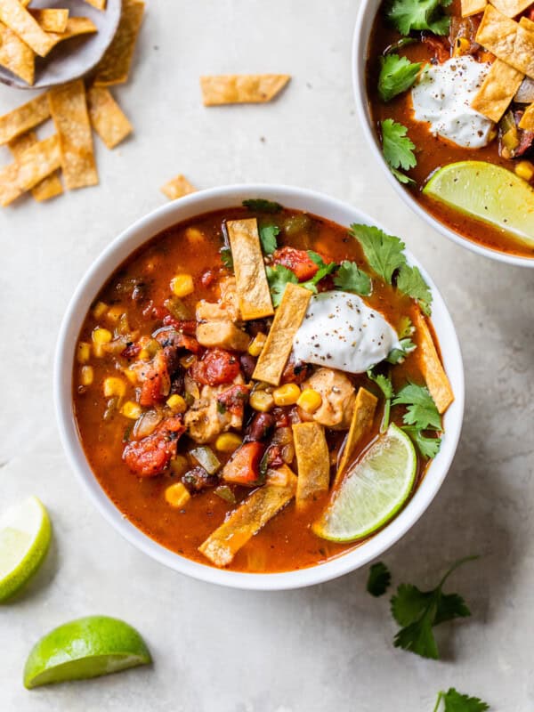 A bowl of southwest chicken soup topped with tortilla strips and sour cream.