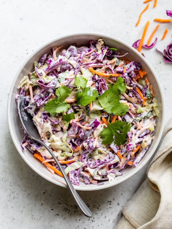 Fish taco slaw in a bowl topped with cilantro leaves.