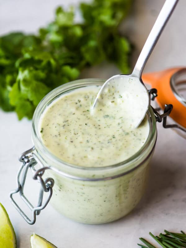 A spoon stirring jalapeno ranch in a jar.