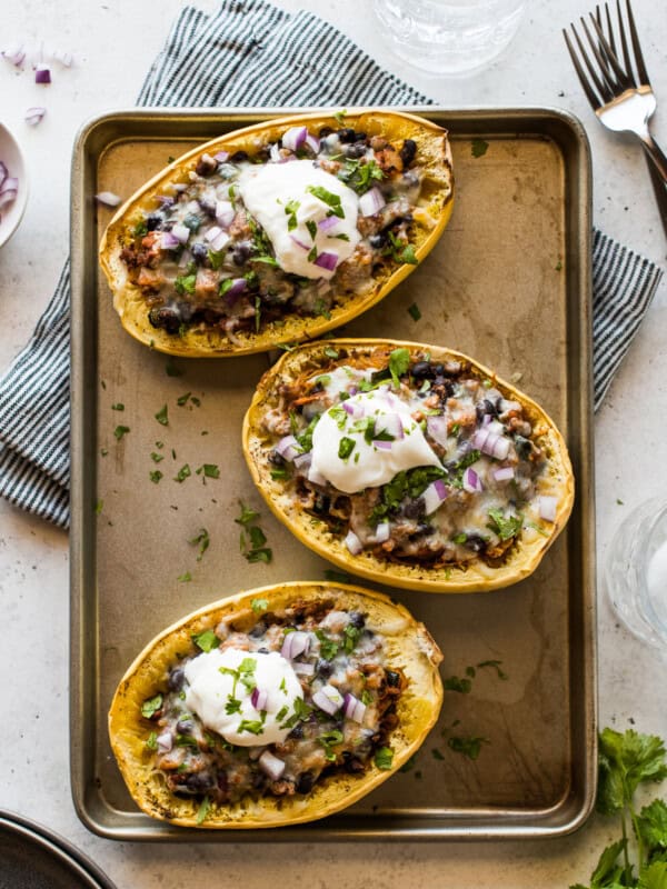 Taco stuffed spaghetti squash topped with cilantro, red onions, and sour cream.