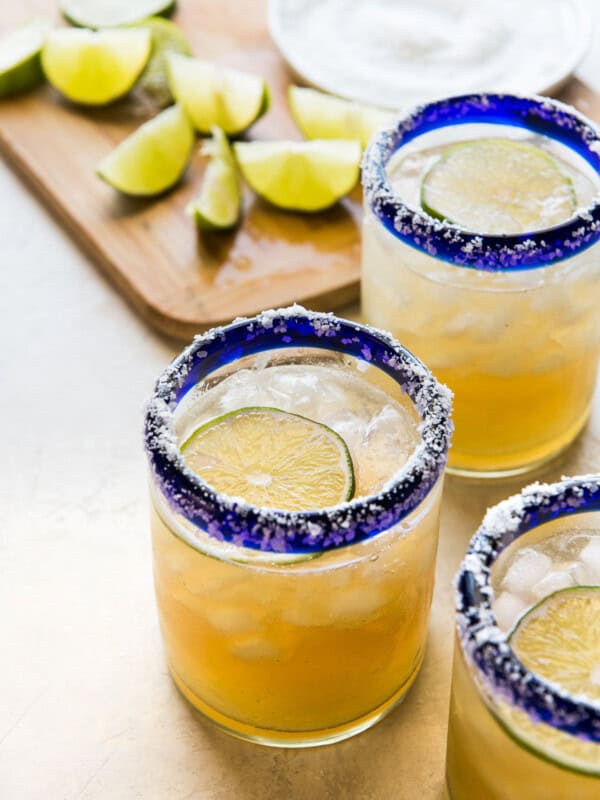 A classic margarita recipe in an iced glass garnished with fresh lime and a salted rim.