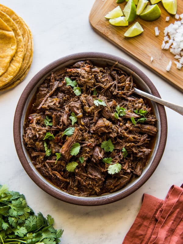 Shredded Instant Pot barbacoa in a large serving bowl garnished with fresh cilantro.