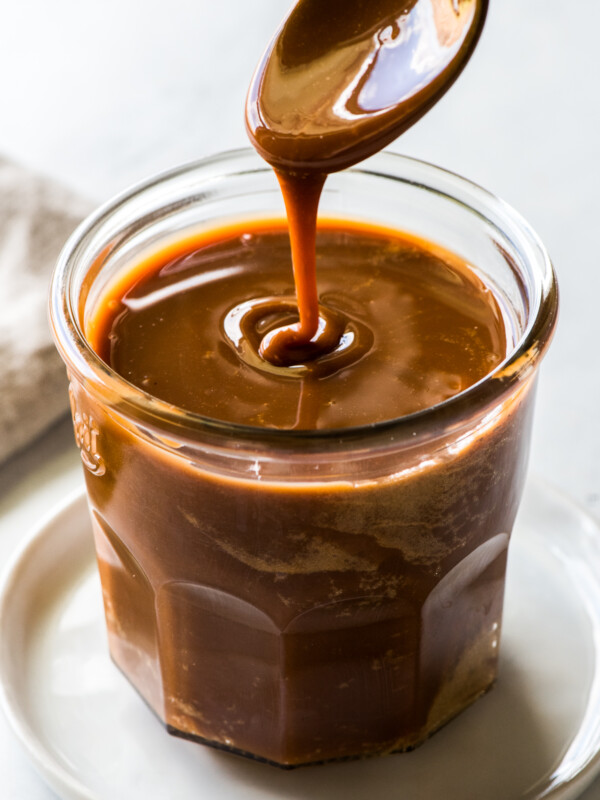 Cajeta pouring from a spoon into a glass jar.