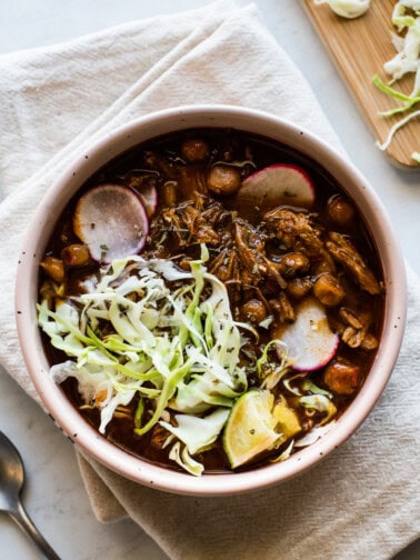 Instant Pot Pozole in a bowl garnished with radishes, shredded lettuce, and a lime.