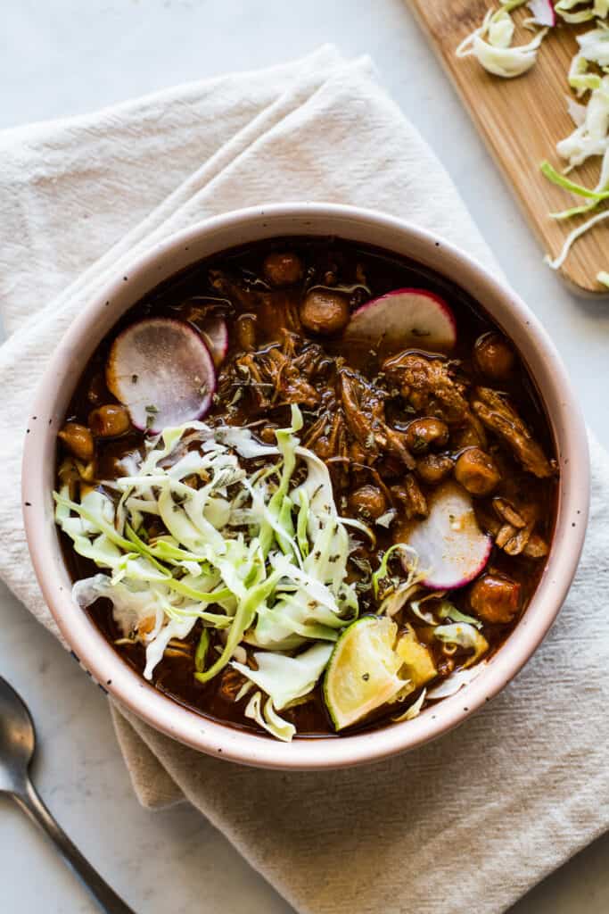 Instant Pot Pozole in a bowl garnished with radishes, shredded lettuce, and a lime.