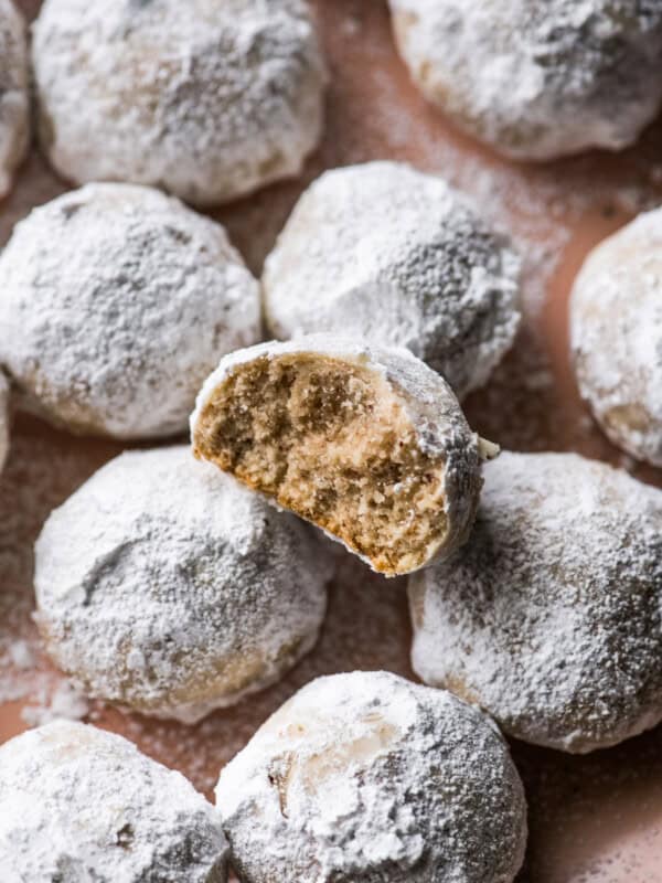 Mexican Wedding Cookies on a plate with one cookie with a bite taken out.