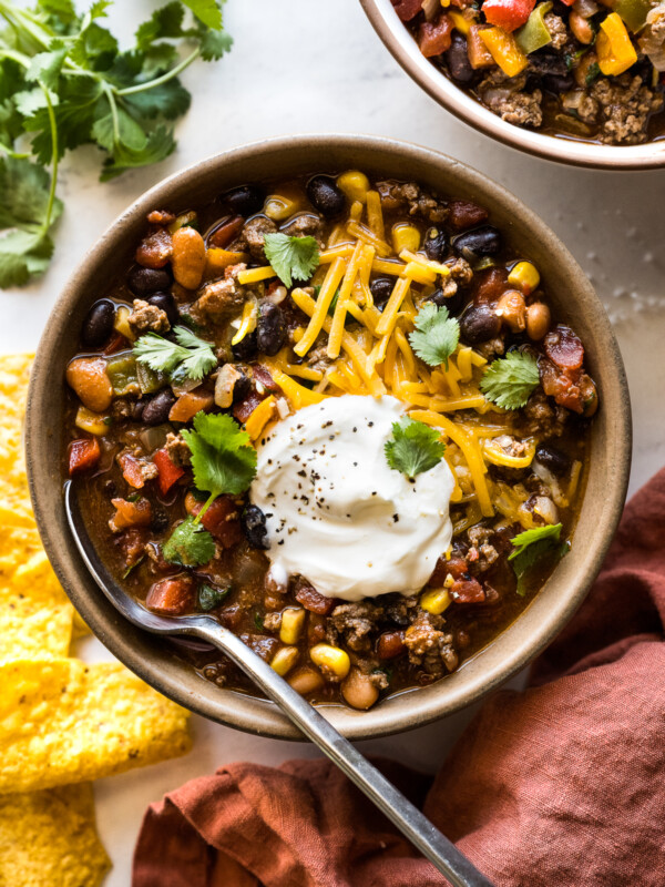 Taco soup in a bowl topped with shredded cheese, sour cream, and cilantro.