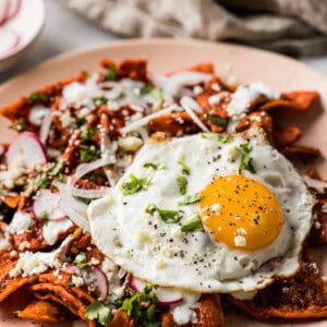 A plate of chilaquiles topped with a fried eggs.